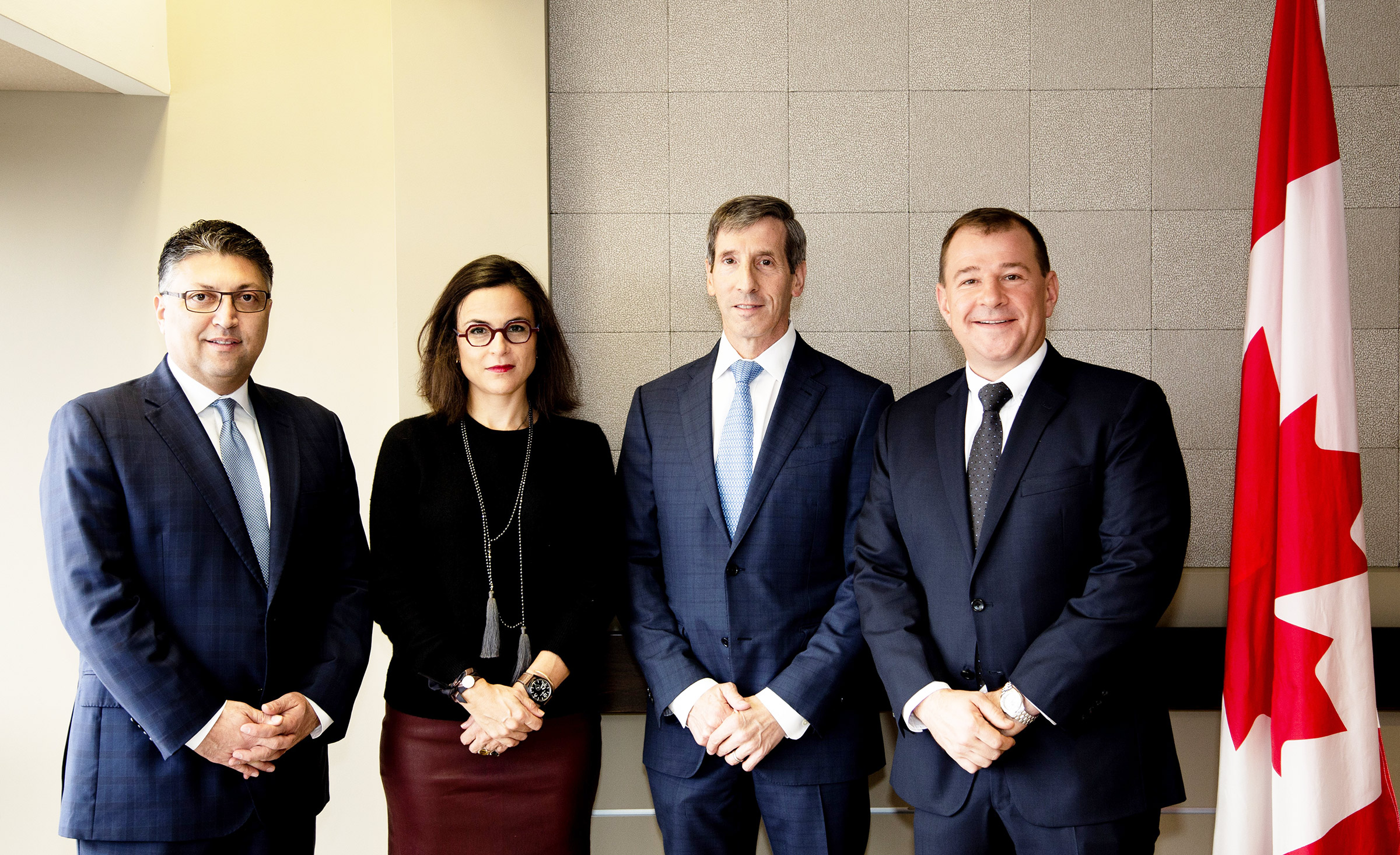 antitrust agency heads standing next to the Canadian flag