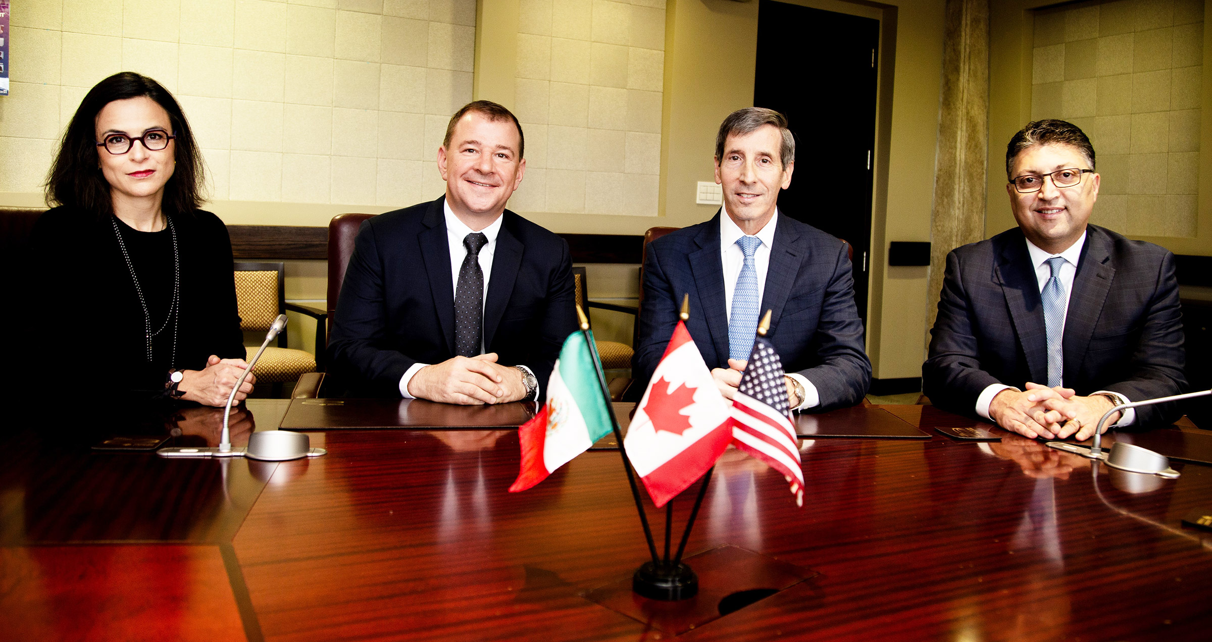 antitrust agency heads seated at a table with small-size versions of their countries' flags