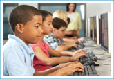 children in a classroom sitting in front of computers