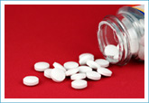 pills spilling out of a bottle on red background