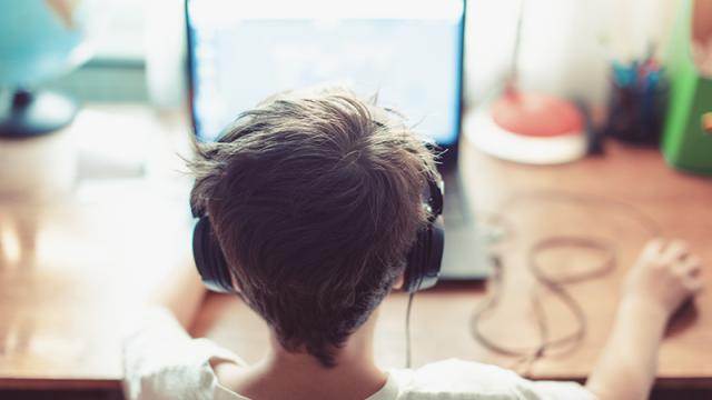 child wearing headphones and sitting in front of a laptop